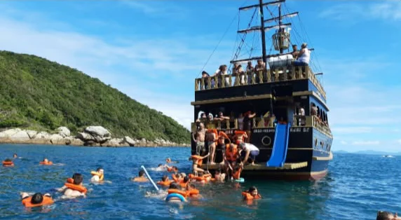 Passageiros de colete nadando ao lado do barco pirata